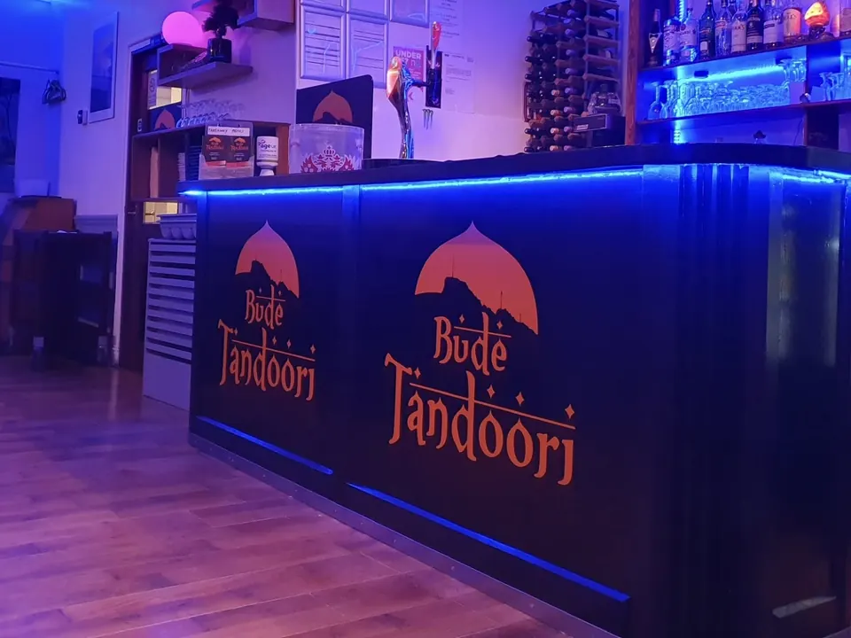 The Bude Tandoori bar, with the orange Bude Tandoori logo on the front and blue lights along the counter.